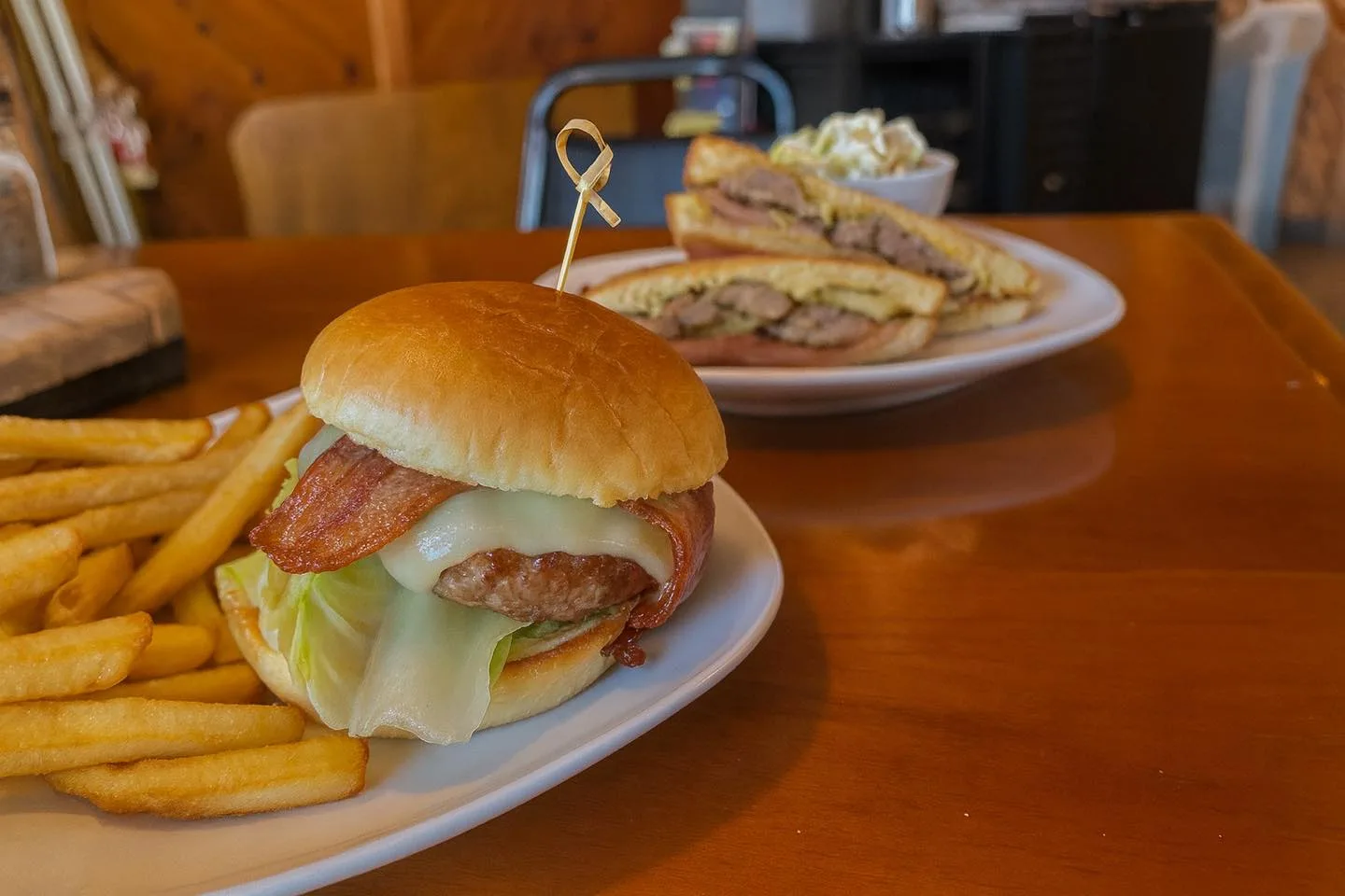 Bacon cheeseburger with fries, a pressed sandwich and coleslaw behind