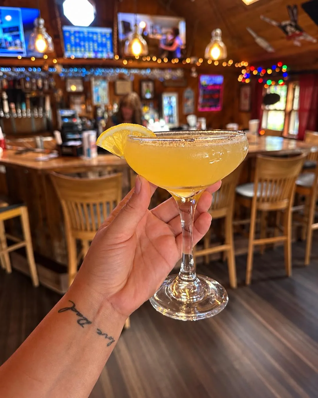 Honey martini in a coupe glass held up in front of the bar